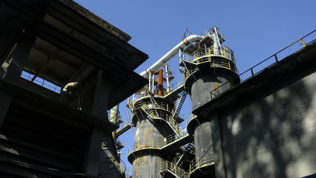 An industrial factory with tall chimneys under a clear blue sky, showcasing industrial architecture.